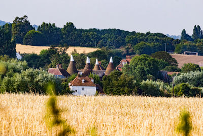 House on field by trees against sky