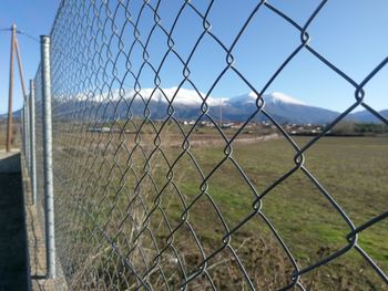 Close-up of fence by field against sky