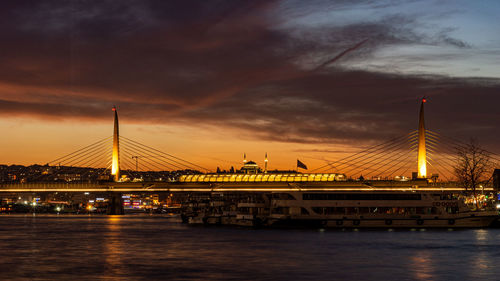 Illuminated bridge over river against sky at night