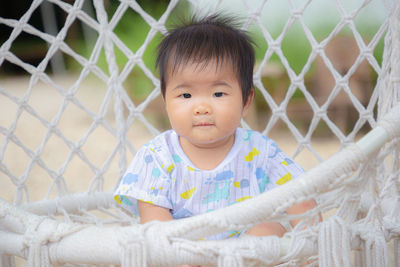 Portrait of cute baby girl looking through fence