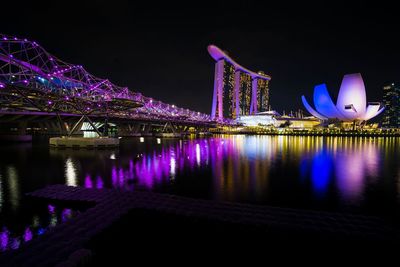 Illuminated bridge over river at night