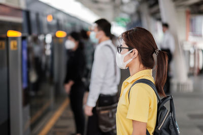 Side view of woman wearing pollution mask while standing at subway station