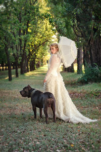 Side view of woman standing with pet dog at park