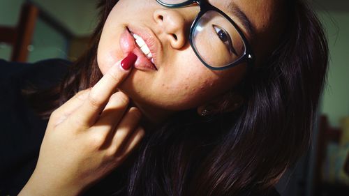 Close-up portrait of young woman with finger on lips