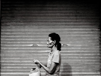 Side view of woman standing against wall