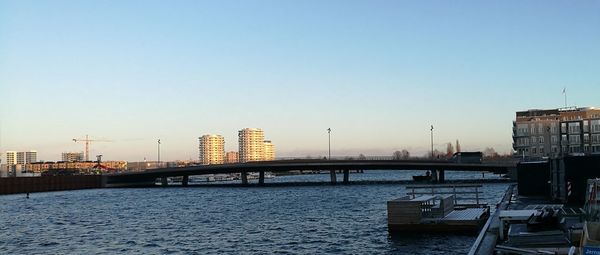 Bridge over river against clear sky during sunset