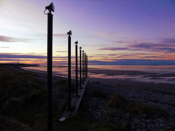 Poles in row at calm beach against the sky