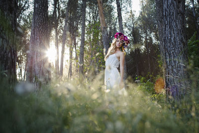 Woman wearing flowers while standing in forest