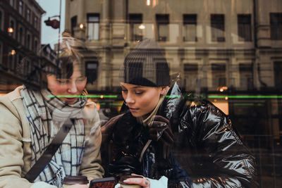 Young man using smart phone in city during winter