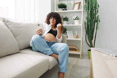 Full length of woman sitting on sofa at home