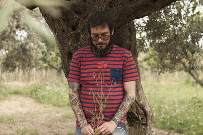 Man holding flower while standing on field