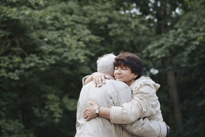 Portrait of senior woman hugging her husband in the woods