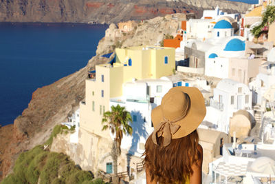 Rear view of woman looking at buildings by sea