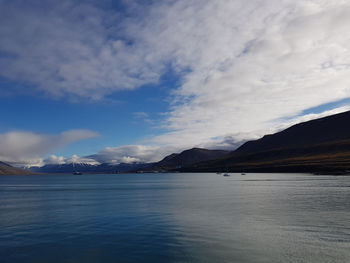 Scenic view of sea by mountains against sky