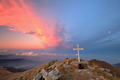 Low angle view of cross on mountain against sky during sunset