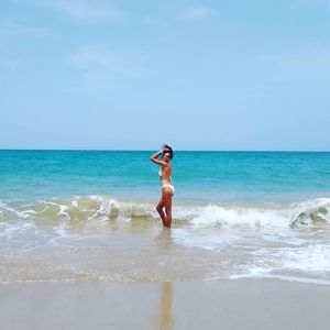 Full length of woman standing on beach against sky