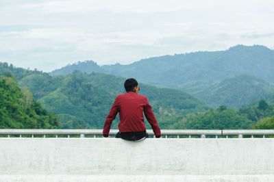 Rear view of man looking at mountains against sky