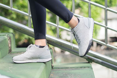 Low section of person wearing shoes on railing