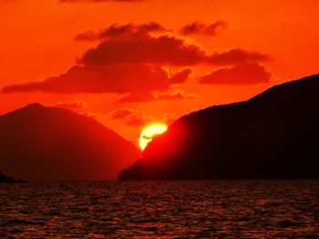 Scenic view of sea in front of mountains against sky during sunset