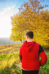 Rear view of man standing on field during autumn