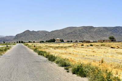 Road leading towards mountains against clear sky