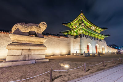 Animal sculpture by illuminated gate at night