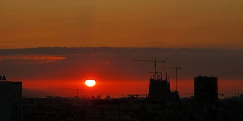 Silhouette buildings in city against romantic sky at sunset