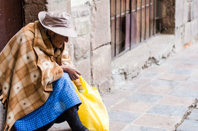 Woman holding umbrella on footpath in city