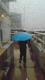 Rear view of person walking on wet window during rainy season