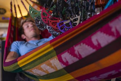 Man sleeping in hammock inside bus under lots of climbing gear hanging