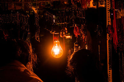 Illuminated light bulbs hanging on street at night