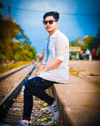 Young man wearing sunglasses on railroad track