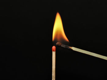 Close-up of burning matchstick against black background