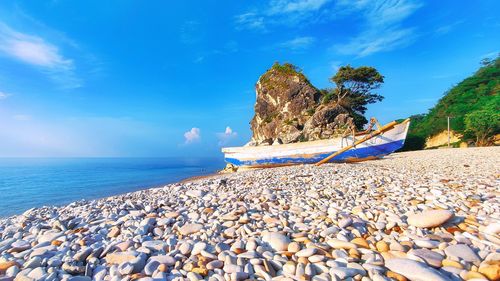 Rocks on beach against blue sky