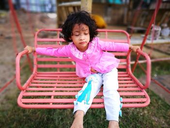 Girl with eyes closed sitting on swing