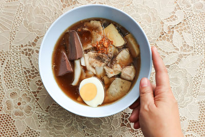 High angle view of hand holding soup in bowl