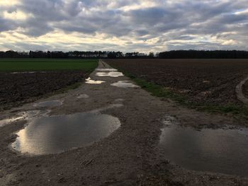 Road amidst field against sky