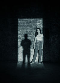 Teenage girl in a dark room and her shadow on the wall