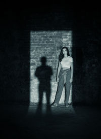 Full length of woman standing against wall