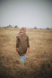 Rear view of woman walking on field
