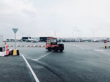 Vehicles on road against sky in city