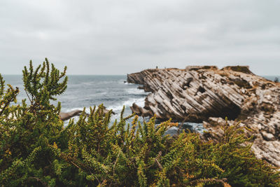 Scenic view of rocks by sea against sky