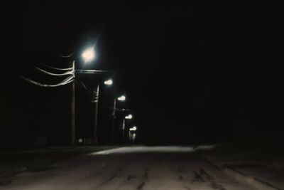 Illuminated street light on road at night