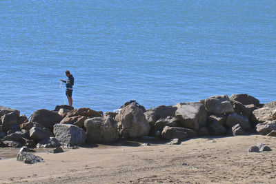 People standing on rocks by sea