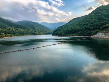 Scenic view of lake by mountains against sky