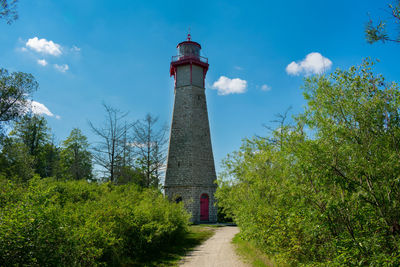 Low angle view of lighthouse amidst trees and buildings against sky