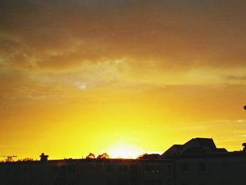 Silhouette houses against sky during sunset