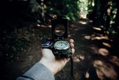 Midsection of person photographing camera in forest