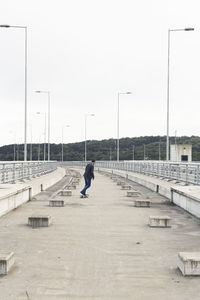 Man walking on bridge against sky