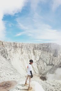 Man standing on rock against sky